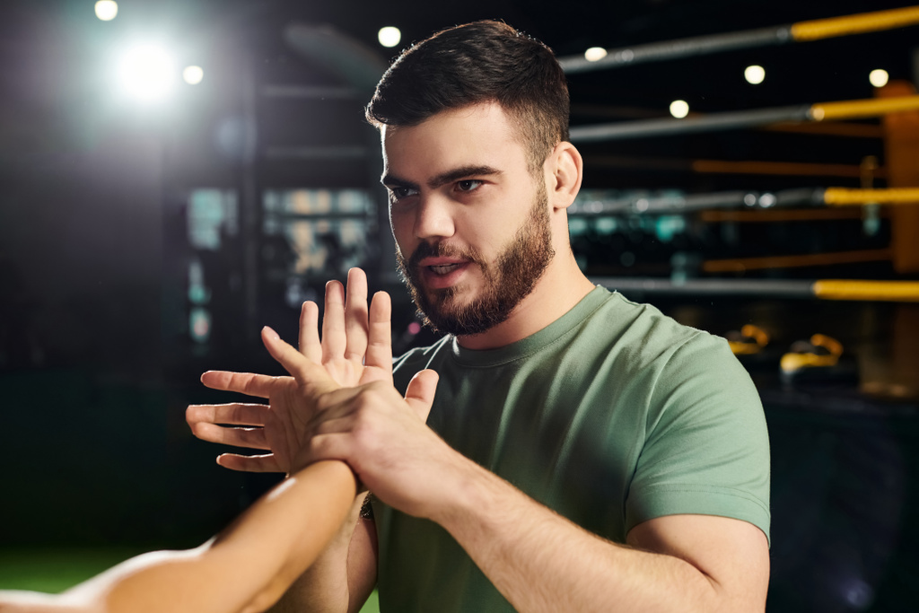 Um homem demonstra técnicas de autodefesa a uma mulher num ginásio à frente de uma câmara.. - Foto, Imagem