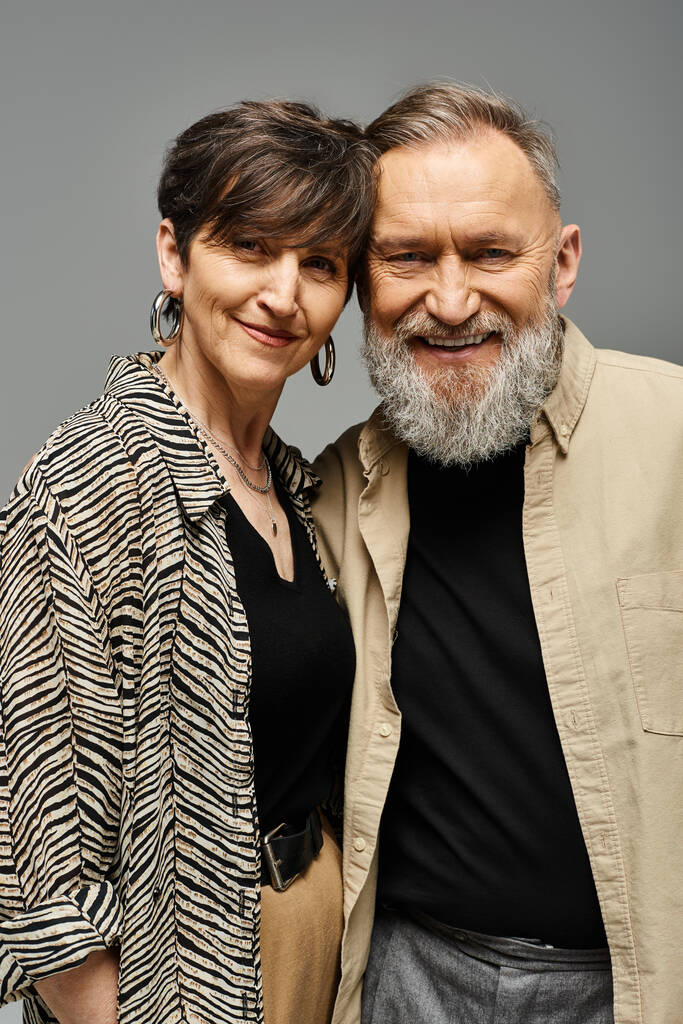 Un hombre y una mujer de mediana edad vestidos con un atuendo elegante de pie uno al lado del otro en un entorno de estudio. - Foto, imagen