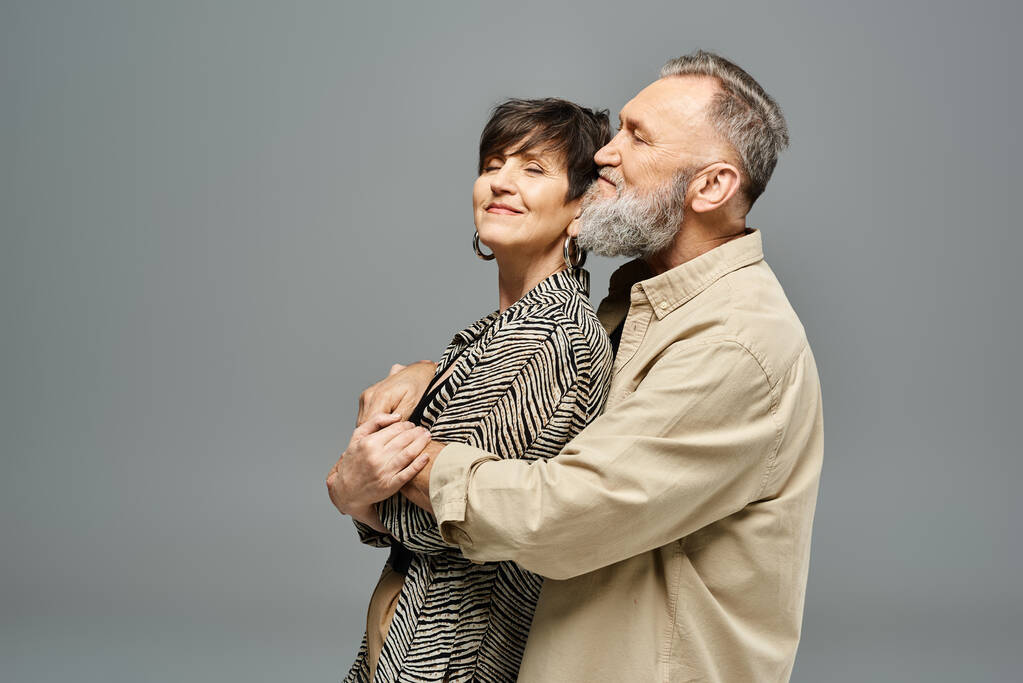 Una pareja de mediana edad con un atuendo elegante abrazándose calurosamente en un entorno de estudio. - Foto, Imagen