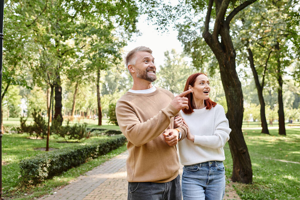 Una pareja, casualmente vestida, disfruta de un tranquilo paseo por un pintoresco parque. - Foto, imagen