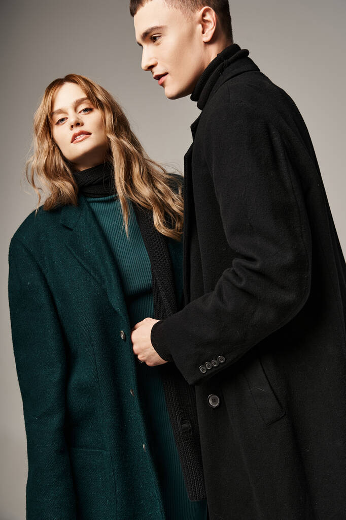atractivo hombre de abrigo posando amorosamente junto a su hermosa novia que mira a la cámara - Foto, imagen
