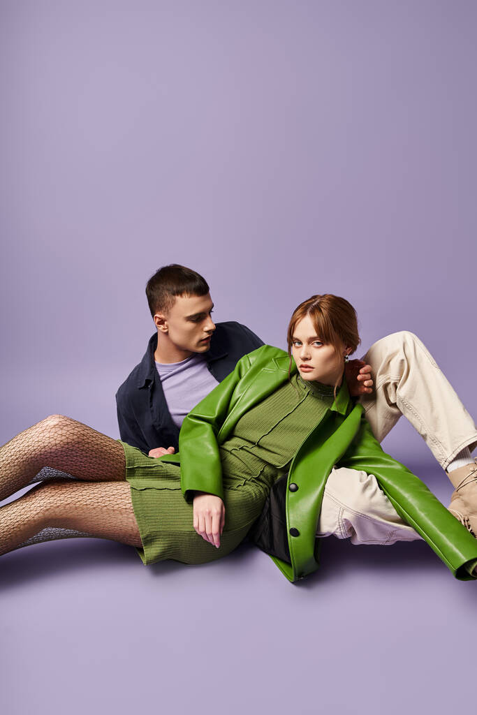 красива стильна жінка в зеленому піджаку сидить на підлозі зі своїм хлопцем і дивиться на камеру - Фото, зображення