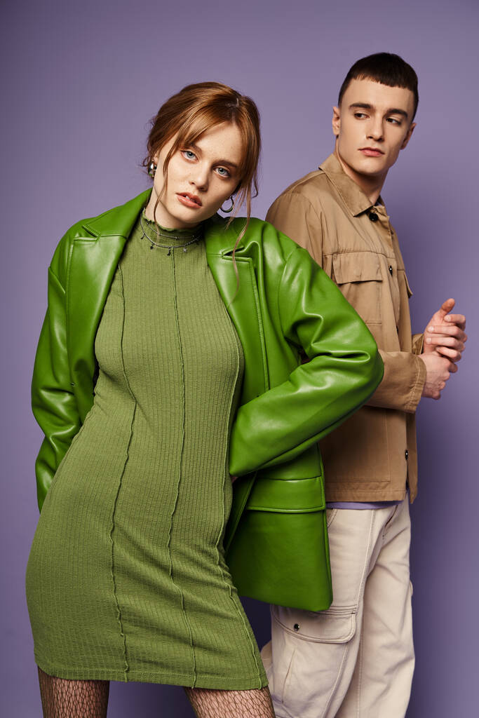 Yeşil elbiseli güzel bir kadın mor arka planda yakışıklı erkek arkadaşının yanında kameraya bakıyor. - Fotoğraf, Görsel