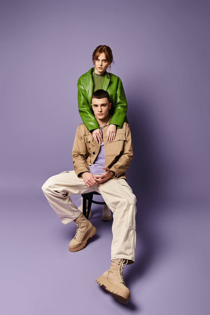 красивый стильный мужчина в коричневой куртке сидит рядом со своей красивой девушкой в ярком наряде - Фото, изображение