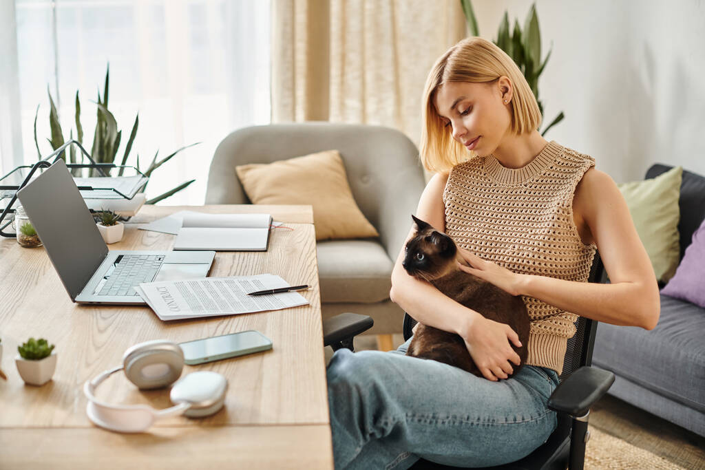 Eine Frau mit kurzen Haaren sitzt friedlich auf einem Stuhl und hält ihre geliebte Katze zu Hause. - Foto, Bild