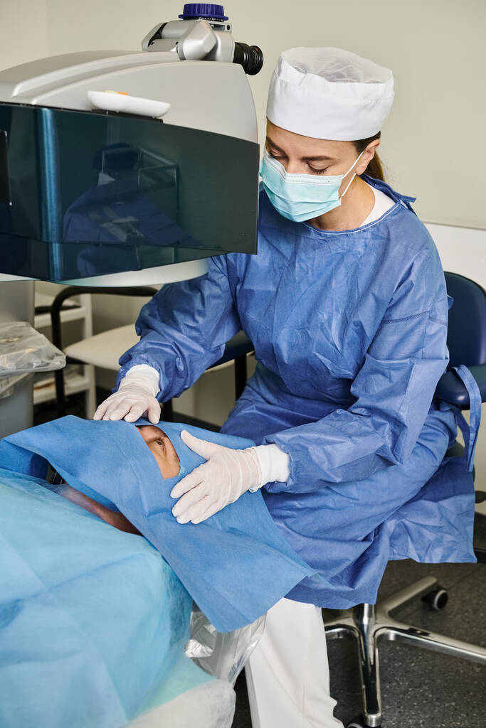 Uma mulher em um vestido de hospital opera uma máquina para correção de visão a laser. - Foto, Imagem