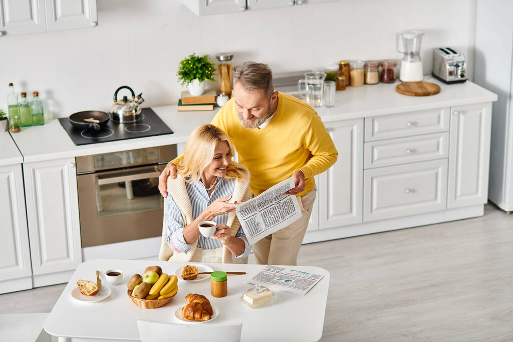 A mature loving couple in cozy homewear spending time together in the kitchen, creating delicious meals and cherished memories. - Photo, Image