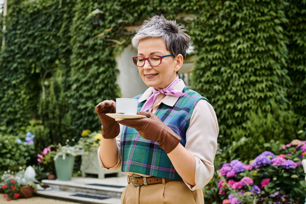 attraktive fröhliche reife Frau trinkt heißen Tee beim Frühstück im Garten ihres Hauses in England - Foto, Bild
