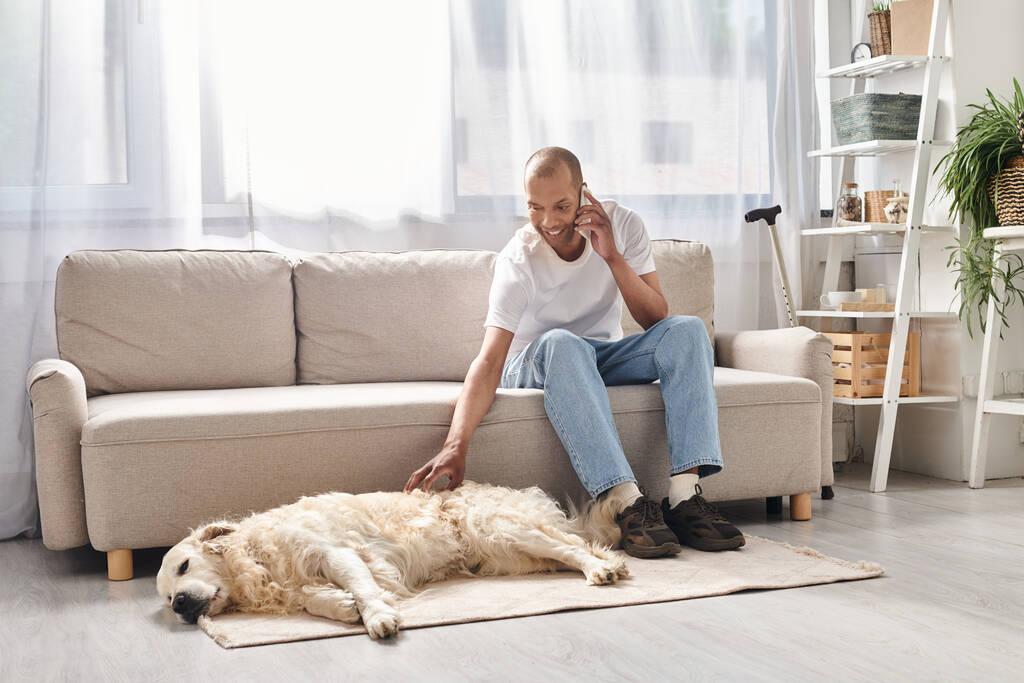 Африканський американець з міастенією гравієм сидить на дивані поруч зі своїм вірним собакою Лабрадором, втілюючи різноманітність і включення. - Фото, зображення
