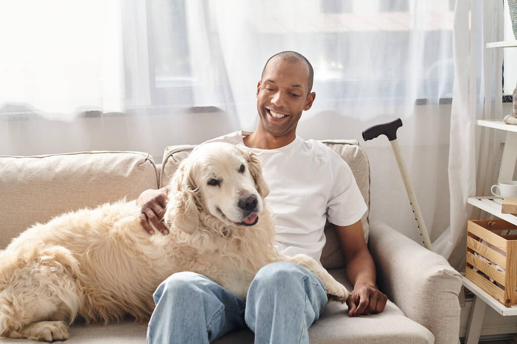 Инвалид афроамериканец с миастенией и его собакой-лабрадором находит утешение на диване дома. - Фото, изображение
