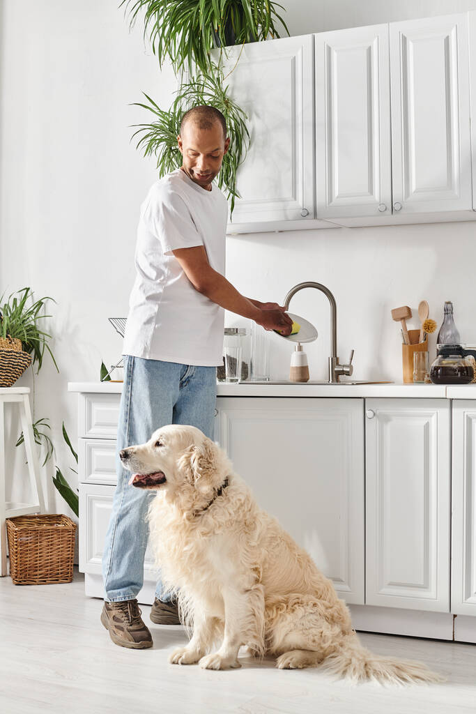 Un Afro-Américain se tient à côté de son chien labrador dans la cuisine, mettant en valeur la diversité et l'inclusion. - Photo, image