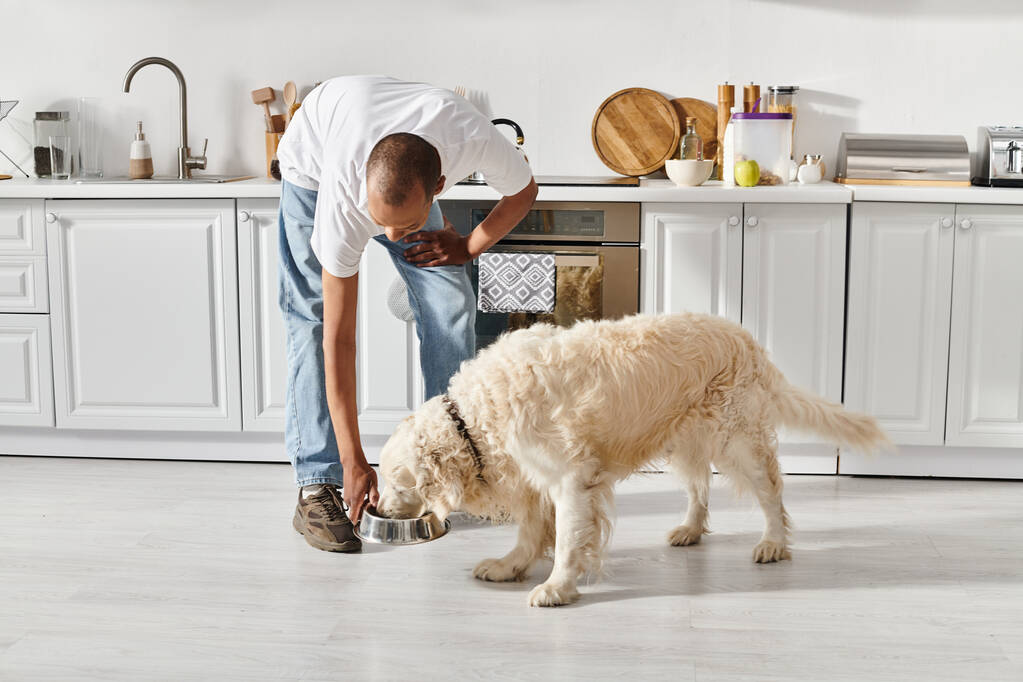 Engelli bir Afrikalı Amerikalı adam ve mutfakta birlikte yemek pişiren sadık Labrador köpeği.. - Fotoğraf, Görsel