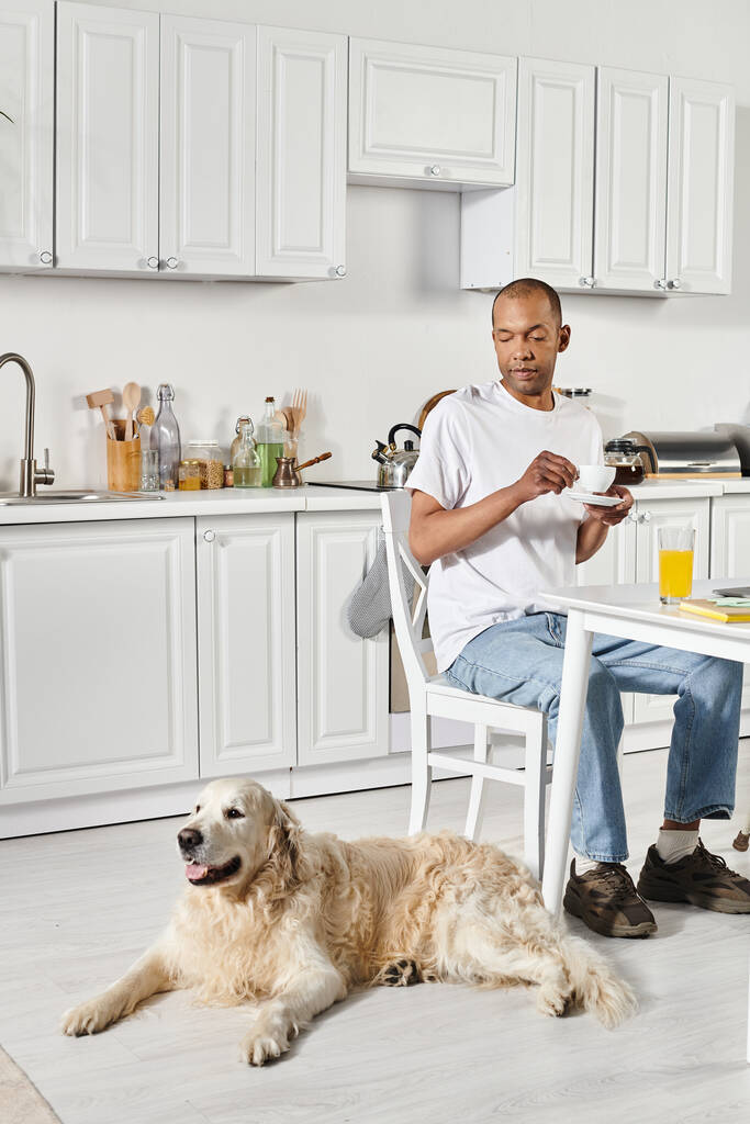 Інвалідний афроамериканський чоловік сидить за кухонним столом зі своїм вірним собакою Лабрадором поруч. - Фото, зображення