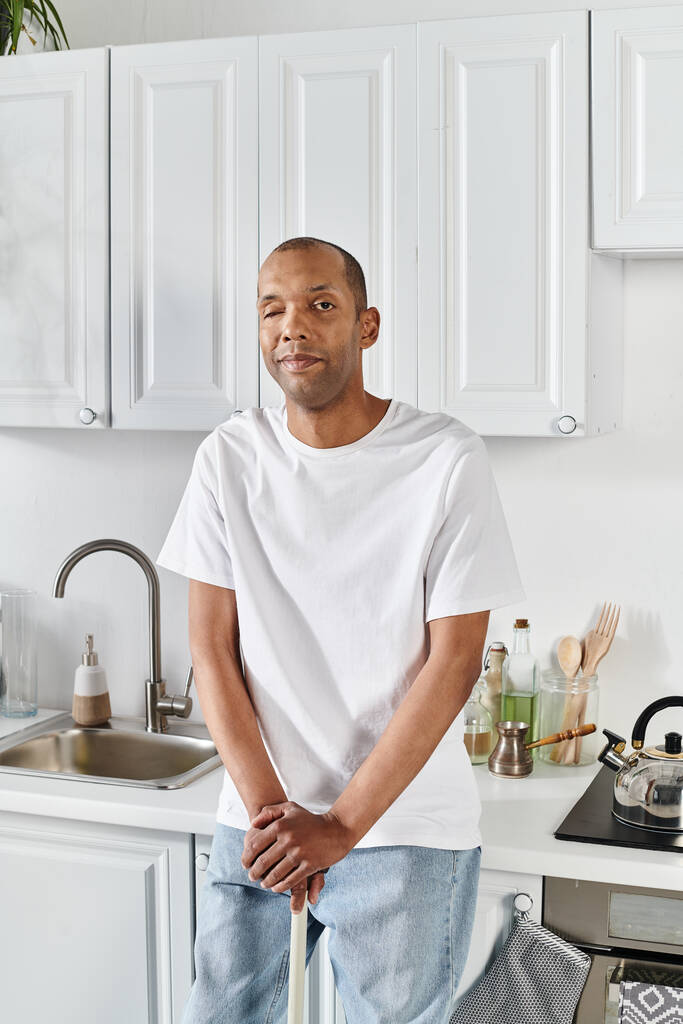 Een Afro-Amerikaanse man met myasthenia gravis syndroom staat vol vertrouwen in een keuken - Foto, afbeelding