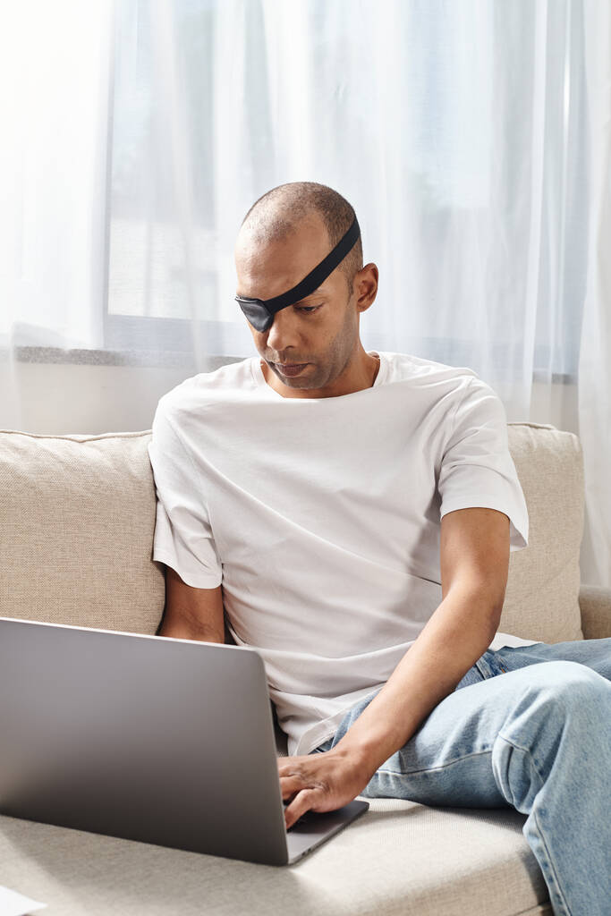 Африканський американець з синдромом міастенії тяжіння використовує ноутбук на дивані. - Фото, зображення