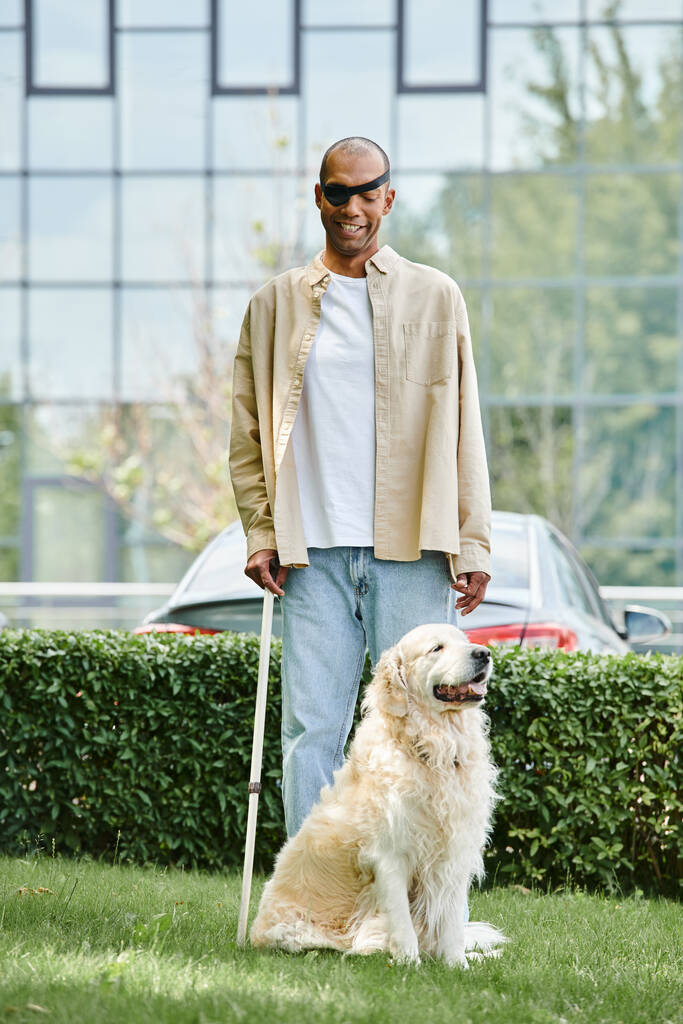 Un uomo afroamericano disabile accanto a un cane Labrador su un lussureggiante campo verde, che simboleggia armonia e inclusività. - Foto, immagini
