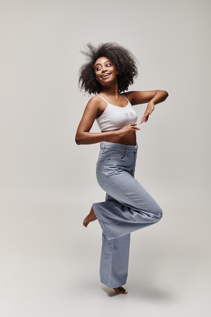 Young African American woman with curly hair performing a pose in a white tank top. - Photo, Image