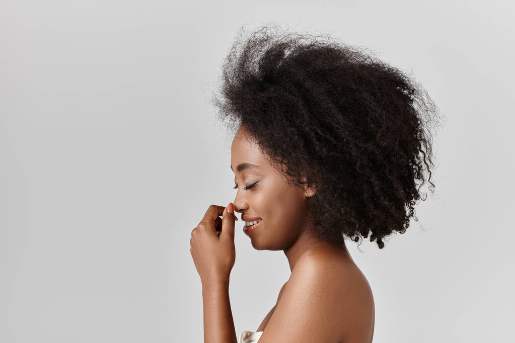 Egy fiatal afro-amerikai nő göndör hajjal magabiztosan pózol egy fotóhoz egy stúdióban, bemutatva a gyönyörű afro. - Fotó, kép
