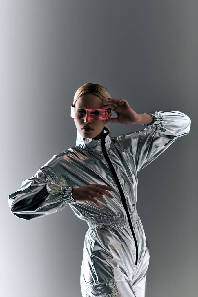 zvláštní žena se sci-fi brýlemi v futuristickém oděvu dělá robotické pohyby a dívá se do kamery - Fotografie, Obrázek