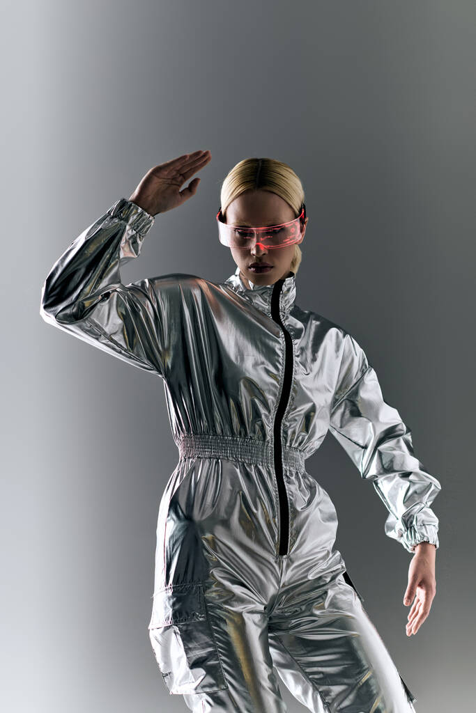 mulher extraordinária com óculos futuristas em traje de prata fazendo movimentos robóticos e olhando para longe - Foto, Imagem