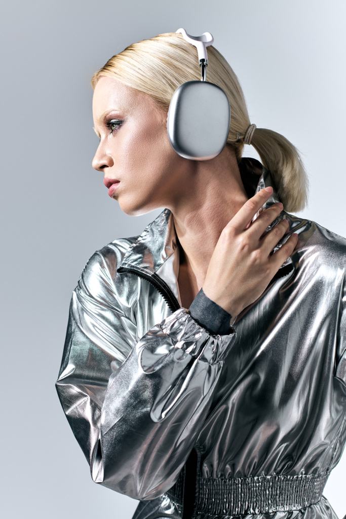 niezwykłe dobrze wyglądająca kobieta ze słuchawkami w futurystyczny srebrny strój cieszący się muzyką - Zdjęcie, obraz