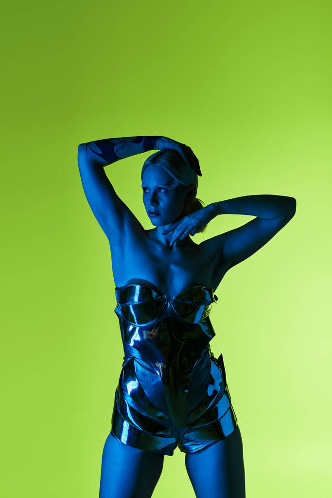 mujer hermosa peculiar en traje de ciencia ficción futurista posando en luces azules sobre fondo verde - Foto, imagen