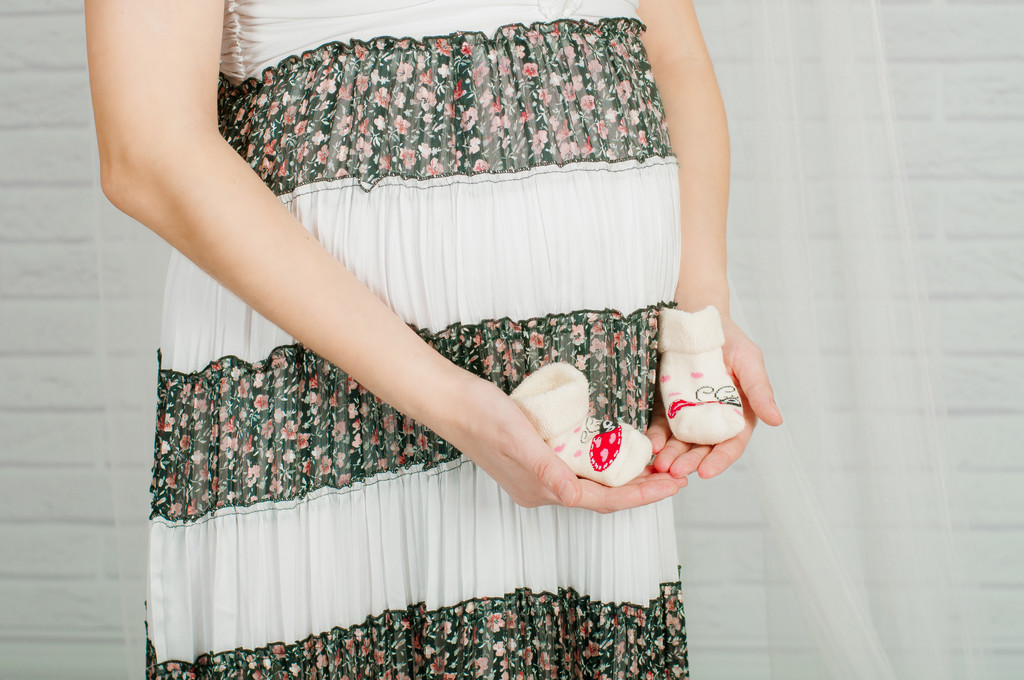 Baby sokken in handen van de zwangere vrouw - Foto, afbeelding