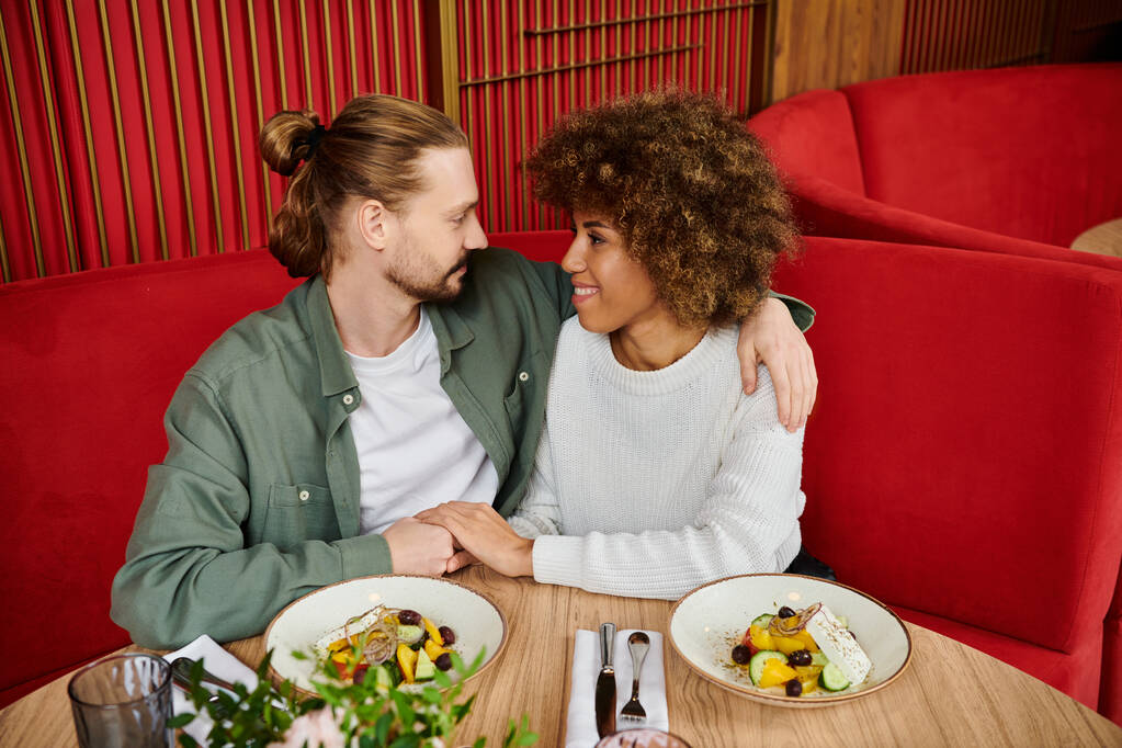 男性と女性がモダンなカフェでテーブルで一緒に食事を楽しむ. - 写真・画像