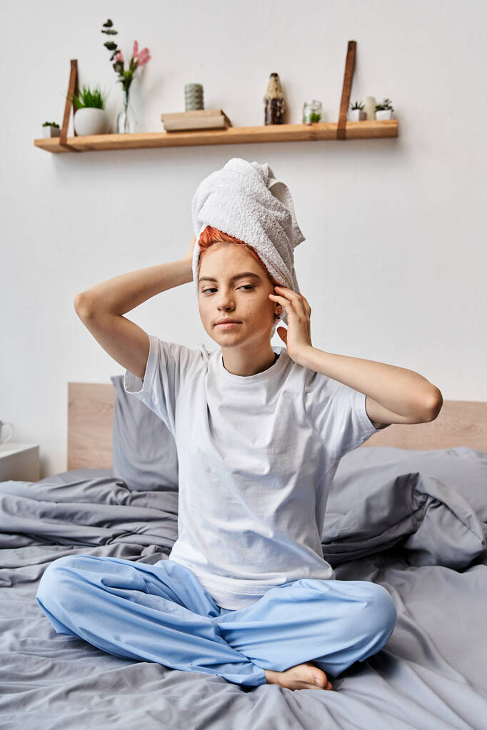 attraente persona stravagante con asciugamano bianco seduto sul suo letto a casa, routine mattutina - Foto, immagini