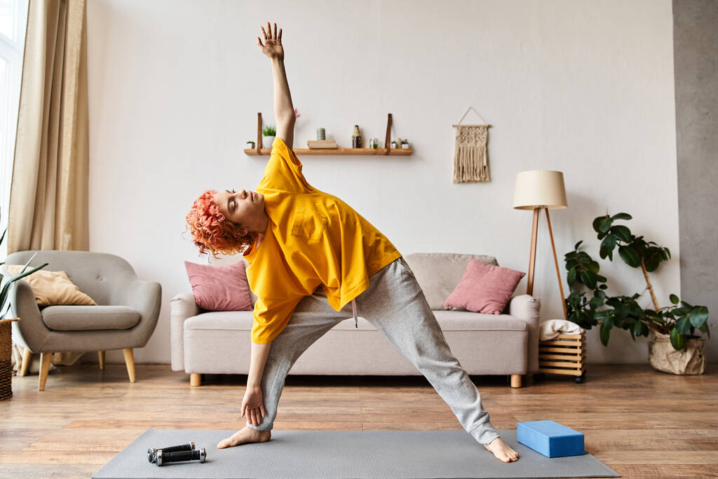 goed uitziende vrolijke queer persoon in casual kleding oefenen actief op yoga mat terwijl thuis - Foto, afbeelding