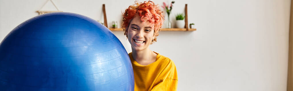joyous queer person in comfy attire exercising with fitness ball and smiling at camera, banner - Photo, Image