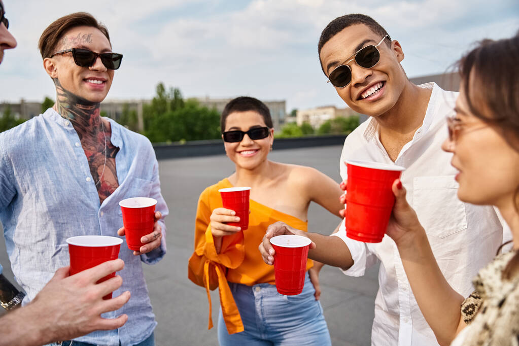χαρούμενους διαφυλετικούς φίλους με κομψά γυαλιά ηλίου που περνούν χρόνο μαζί στο πάρτι στην ταράτσα - Φωτογραφία, εικόνα