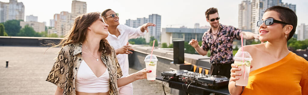 vesele rozmanití přátelé se slunečními brýlemi pijící na střešní párty a tančící na DJ set, banner - Fotografie, Obrázek