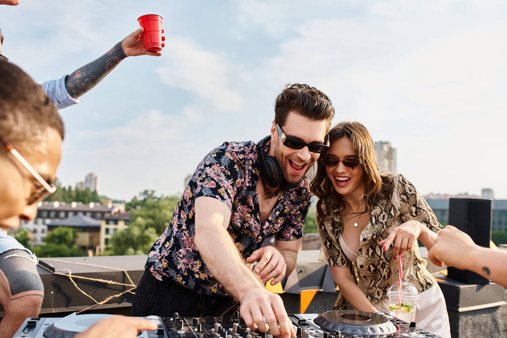 joyful multiracial přátelé s trendy sluneční brýle mají skvělý čas na střešní party s DJ - Fotografie, Obrázek