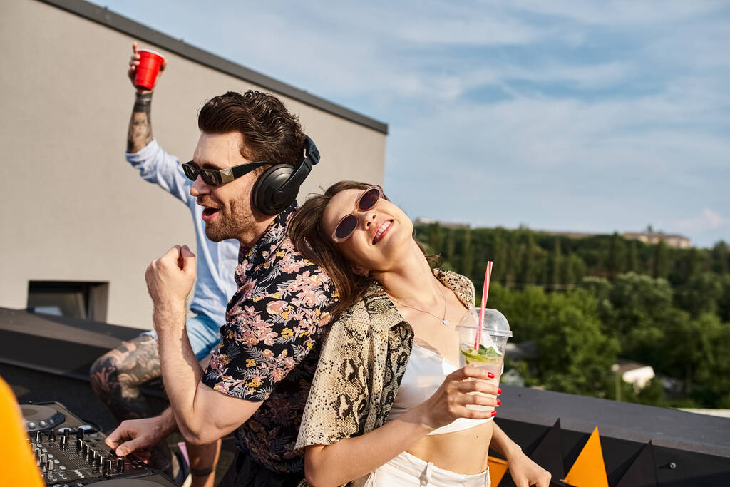 amigos alegres de buen aspecto en trajes urbanos con gafas de sol elegantes beber y fiesta en el techo - Foto, imagen