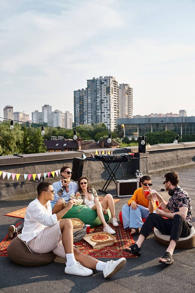 веселые разнообразные молодые друзья в повседневных нарядах в солнцезащитных очках, наслаждающиеся пиццей и напитками на вечеринке - Фото, изображение
