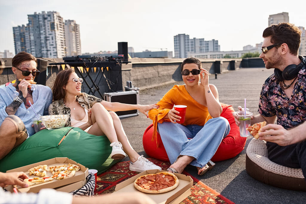 csinos vidám barátok városi ruhák ül a tetőn eszik pizza és koktélok - Fotó, kép