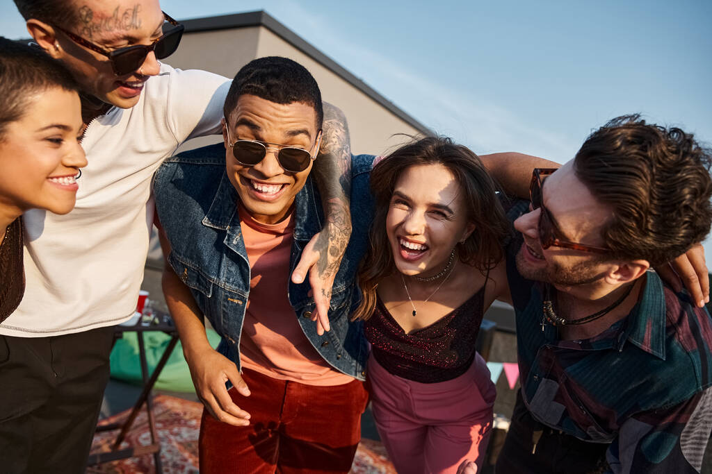 vrolijk aantrekkelijke multiraciale mensen in levendige kledij glimlachen gelukkig op de camera op het dak partij - Foto, afbeelding
