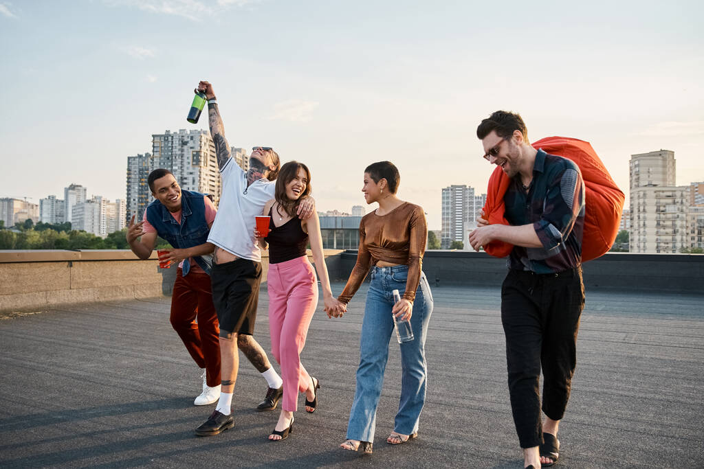 joyous multiracial friends with different drinks and bean bag chair in hands at rooftop party - Photo, Image