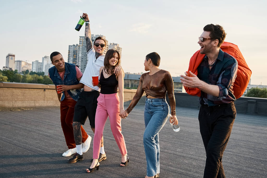 merry interracial friends in urban clothes with different drinks and bean bag chair at rooftop party - Photo, Image