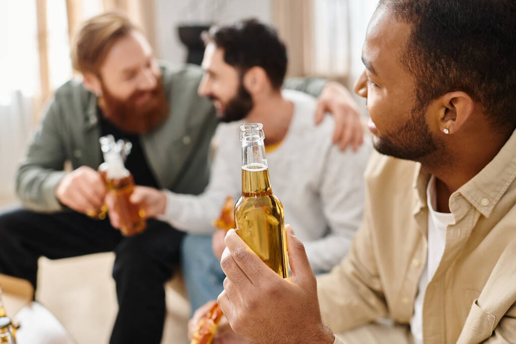 Tři veselí, různé rasy muži v ležérní oblečení sedí kolem stolu, sblížení nad pivem a užívají si spolu dobrý čas. - Fotografie, Obrázek