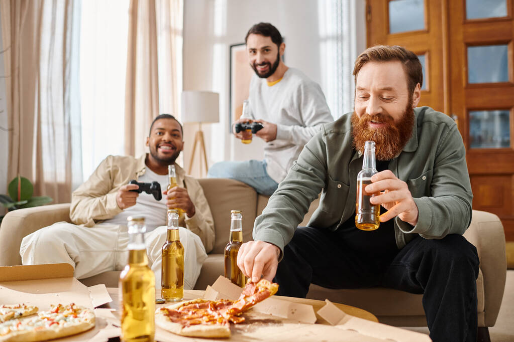 Tres hombres guapos e interraciales disfrutando de pizza y cerveza en una reunión informal, compartiendo risas y buenos momentos en la mesa. - Foto, Imagen