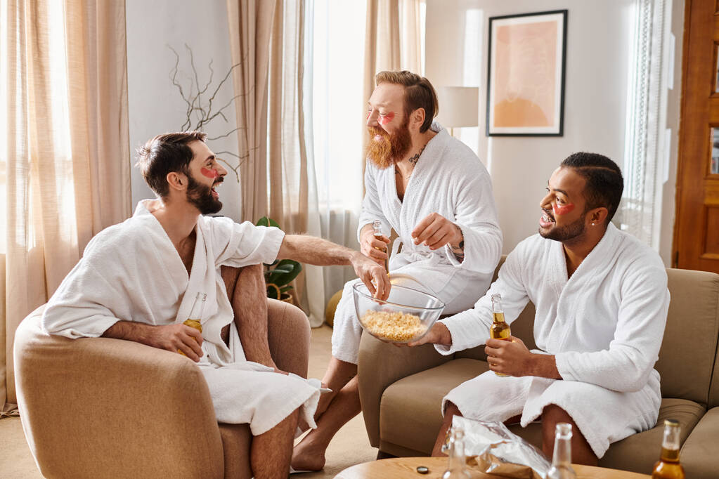 Τρεις χαρούμενοι άντρες με διαφορετικό υπόβαθρο κάθονται σε ένα σαλόνι, απολαμβάνοντας ο ένας τον άλλο παρέα και φιλία.. - Φωτογραφία, εικόνα