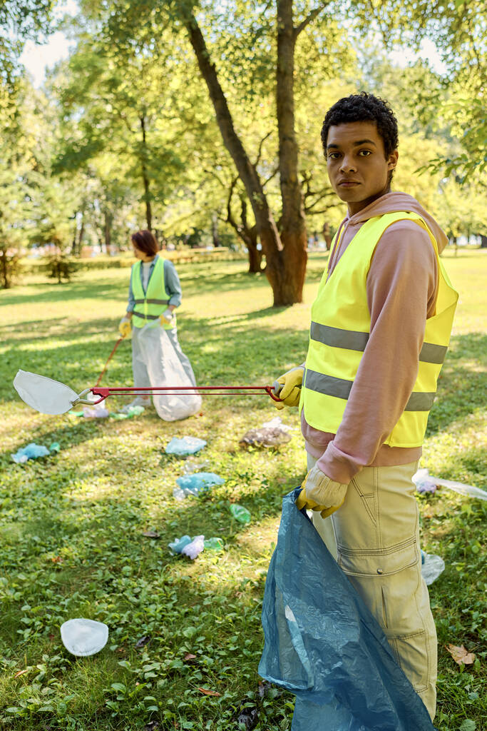 Társadalmilag aktív, változatos pár együtt takarít egy parkot. - Fotó, kép