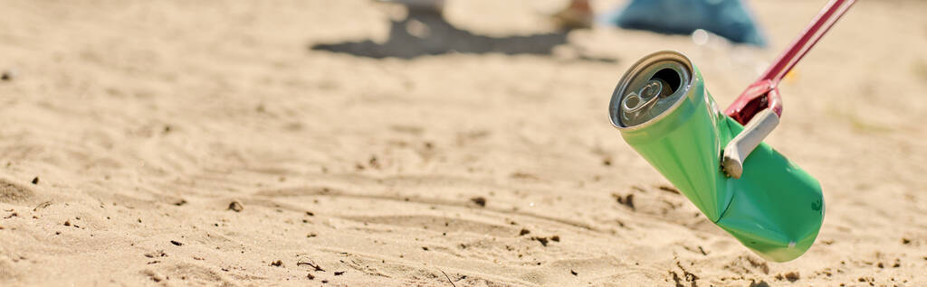 Una lattina di soda penzola da una corda sulla spiaggia, gettando ombre giocose nella sabbia. - Foto, immagini