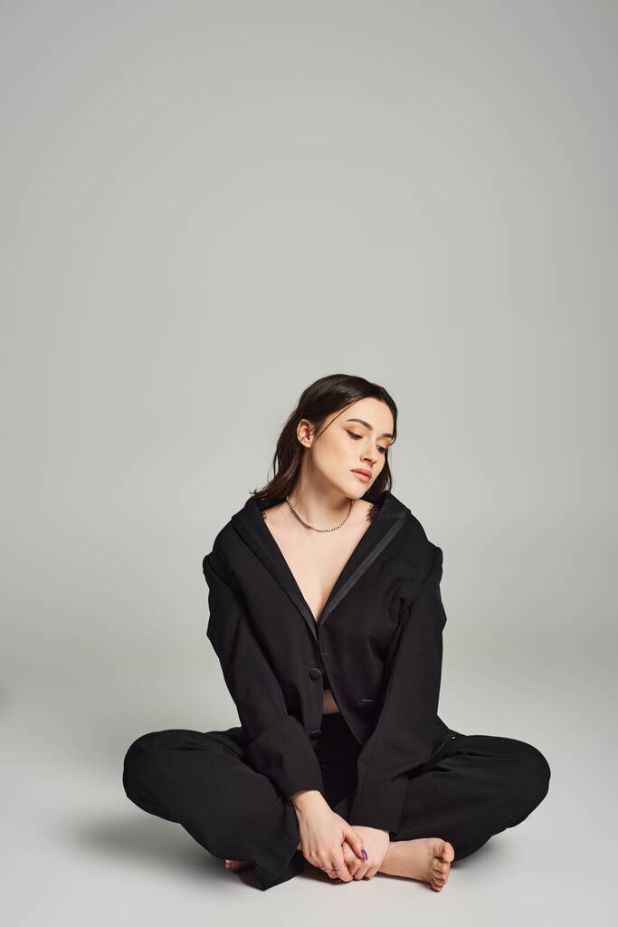 Eine schöne Plus-Size-Frau in stylischer Kleidung sitzt mit geschlossenen Augen auf dem Boden und strahlt Ruhe und Introspektion aus. - Foto, Bild