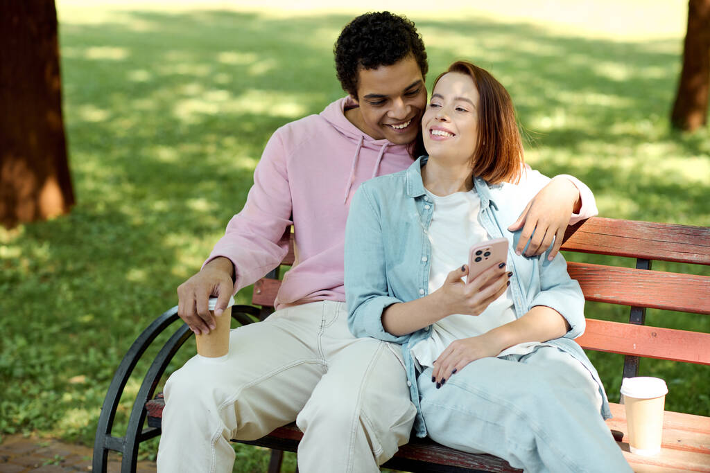 Různorodý pár v pulzujících šatech sedí na lavičce v parku, užívají si společnost za slunečného dne. - Fotografie, Obrázek
