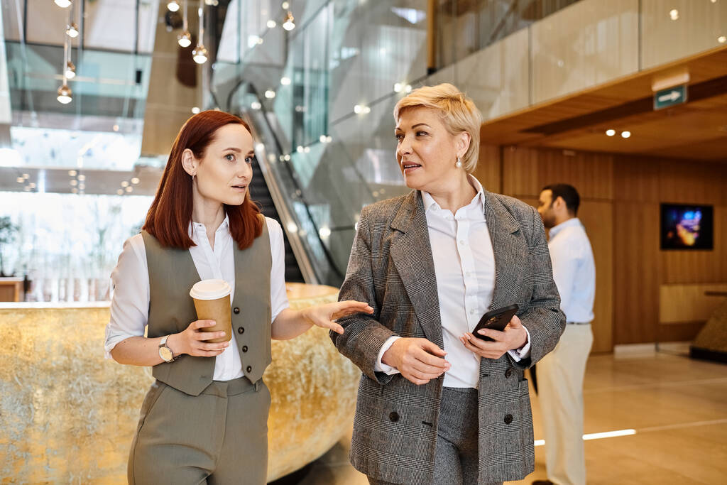 Due donne impegnate in una conversazione in un ambiente hall moderno. - Foto, immagini