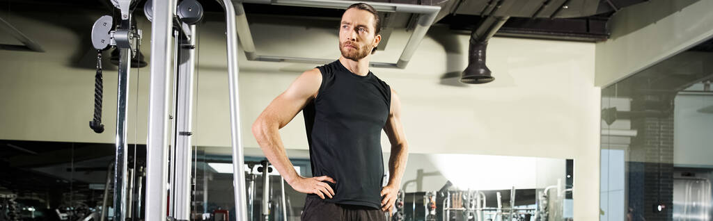 An athletic man in active wear standing in a gym, hands on hips. - Photo, Image