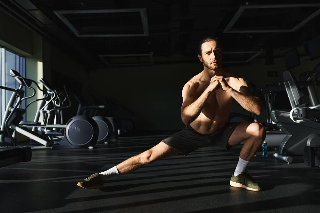 М'язистий чоловік без сорочки, присідаючи на одну ногу в спортзалі. - Фото, зображення